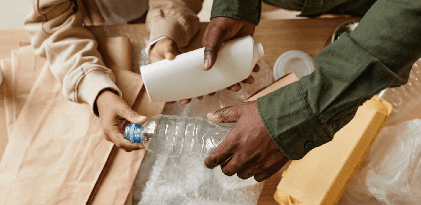 Homem e mulher dispõem garrafas plásticas em uma mesa, refletindo a responsabilidade ambiental e a melhoria na gestão condominial.